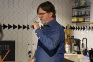 Porträttbild på vinmakaren Fredrik Johansson som luktar på ett glas vin