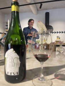 Flaskbild på vinet resa med vinglas och vinmakaren Fredrik Johansson i bakgrunden