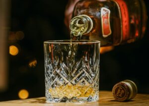 whiskey eller whisky på Systembolaget, en hand häller upp whisky ur en flaska i ett glas